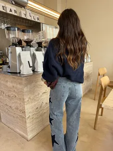 Detailed back view of women's wide-leg denim pants featuring side black star patches in a cafe