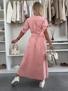 Back view of a pink denim button-front maxi dress in a stylish closet setting