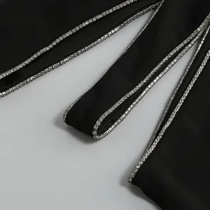 Detail van een sexy zwarte jurk met uitsnijdingen en zilveren strass-afwerking