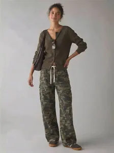 Full body view of a woman wearing camouflage cargo pants and a green cardigan.