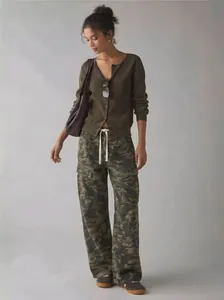 Full shot of woman in camo cargo pants and olive cardigan against grey background