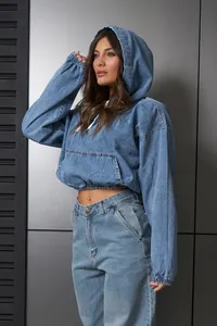 Vista detallada de una sudadera corta de denim azul lavado con capucha y cintura elástica.