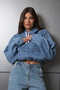 Detalle de una sudadera corta de denim azul lavado con cintura elástica y capucha ajustable