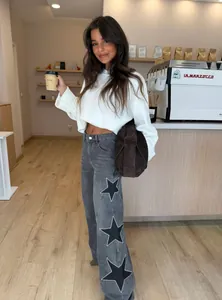 Detail view of grey wide-leg jeans featuring sparkling rhinestone star patterns on the side.