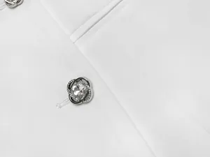 Gros plan de boutons élégants incrustés de cristaux sur une robe blazer blanche de luxe