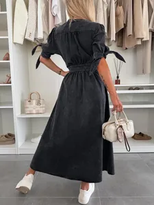 Back view of a stylish dark wash denim midi dress with bow-tied sleeves in a walk-in closet