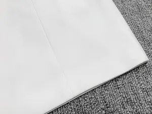 Vue détaillée de la texture du tissu blanc de la robe blazer et de l'ourlet bien fini