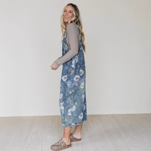 Stylish light blue denim overall dress with white floral print for a casual summer look