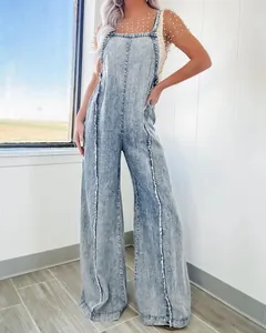 Full-length detail of vintage washed denim overalls with raw edges and wide-leg cut