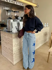 Women's casual light blue straight leg jeans with blue star patches in cafe setting