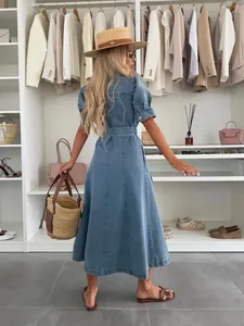 Short sleeve denim midi dress with waist belt shown in a stylish closet setting.