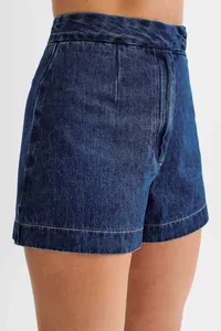 Close-up detail showing the texture and fit of high-waisted dark blue denim shorts on a model