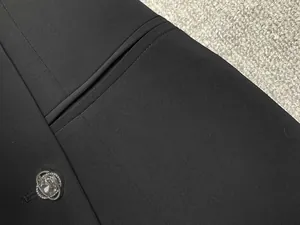 Vue détaillée d'une robe blazer noire avec un bouton en strass étincelant et une poche.