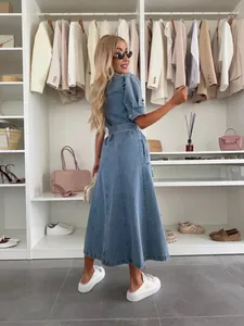 Detail view of a short-sleeved denim midi dress with a belted waist in a closet setting