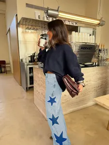 Lifestyle detail of women's light blue jeans with large blue star embroidery patches