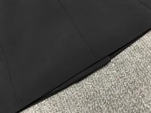 Gros plan sur l'ourlet de la robe blazer noire, montrant la texture et la couture