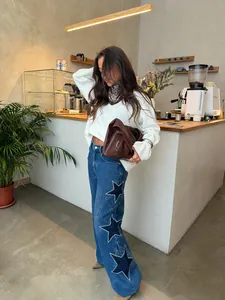 Lifestyle view of women's straight denim pants with bold star patches in a cafe.