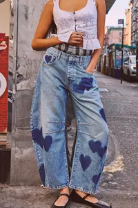 Detail view of baggy barrel-leg denim jeans with dark blue heart patterns in street style.