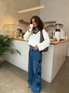 Lifestyle view of wide-leg blue denim jeans with unique star patch embroidery on the side.