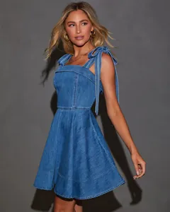 Detail view of denim mini dress featuring stylish bow-tie shoulder straps