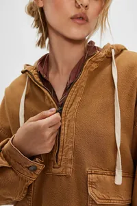Détail en gros plan sur la texture denim lavé et le zip de ce haut à capuche marron