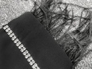 Gros plan du poignet d'une robe blazer noire avec des strass doubles et des plumes
