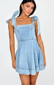 Detailed shot of a light blue denim mini dress featuring bow tie shoulder straps.