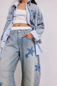 Detail shot of light wash straight jeans featuring blue star patch designs for women.
