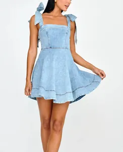Detail of light blue denim mini dress with elegant bow shoulder straps and flared hem