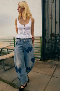 Street style view of casual baggy barrel jeans with heart patches and white eyelet top