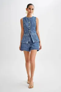 Detail view of denim sleeveless vest and high waist shorts on a female model