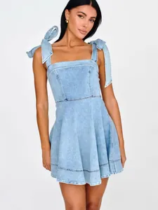 Stylish light blue denim mini dress with bow tie straps for summer fashion look.