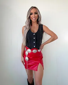 Modèle présentant un gilet en jean noir clouté avec une jupe en cuir rouge vif