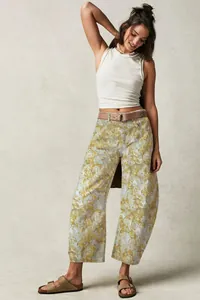 Full body view of a woman wearing loose floral print barrel-leg trousers with sandals