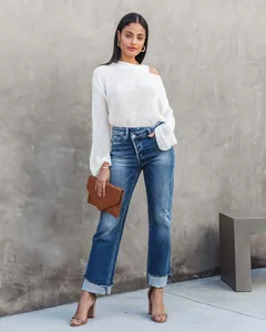 Detail view of women's straight-leg washed blue jeans with cuffed hems and cross-waist design.