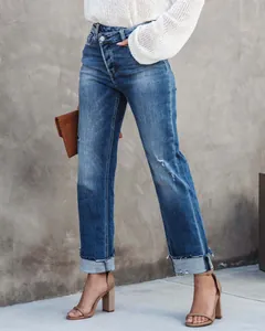 Detail of women's straight-leg denim jeans with crossover waist and cuffed raw hems.