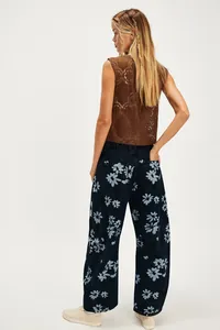 Back view of women's loose dark blue barrel jeans with light blue floral pattern detail