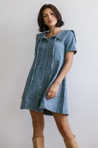 Model draagt een stijlvolle blauwe spijkerjurk met luipaardprint voor witte muur