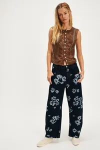 Female model wearing loose black barrel leg jeans with blue floral prints