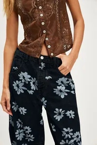 Detailed view of women's relaxed mid-rise denim pants featuring a light blue floral print