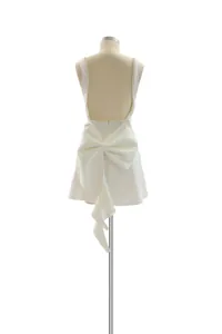 Rear view of white backless mini dress with oversized pearl-trimmed bow detail
