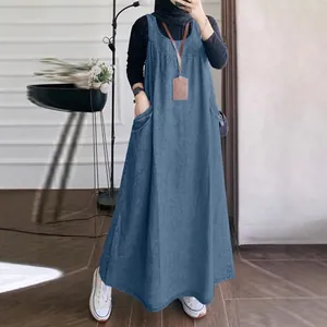 Detail view showing the loose-fitting denim pinafore dress design with convenient pockets