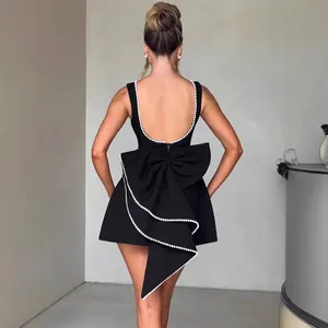 Elegant black backless A-line mini dress featuring a large statement bow with pearl trim detail