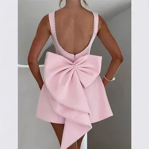 Elegant pink backless mini dress featuring a large pearl-trimmed bow decoration