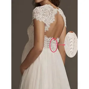 Detail view showing the adjustable lace-up back of an elegant white maternity wedding gown
