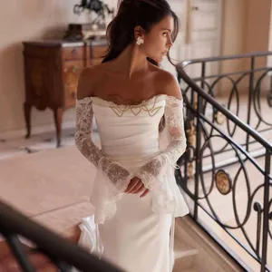 Close-up of elegant white off-the-shoulder lace sleeve wedding dress with heart embroidery