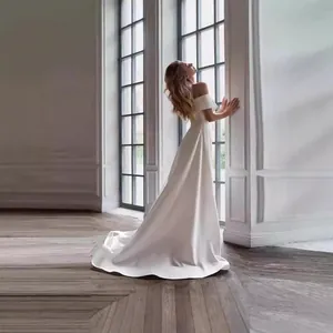 Elegantes schulterfreies Brautkleid aus weißem Satin im minimalistischen französischen Stil.