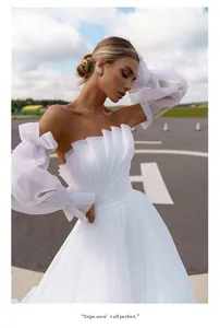 Close-up of elegant white pleated strapless wedding dress with puff sleeves