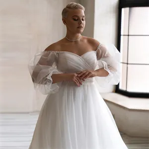 Detail of off-the-shoulder wedding dress with puffy sheer sleeves and A-line silhouette.