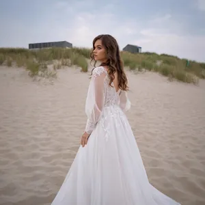 Elegant lace V-neck wedding dress with long puff sleeves and open back on a beach.